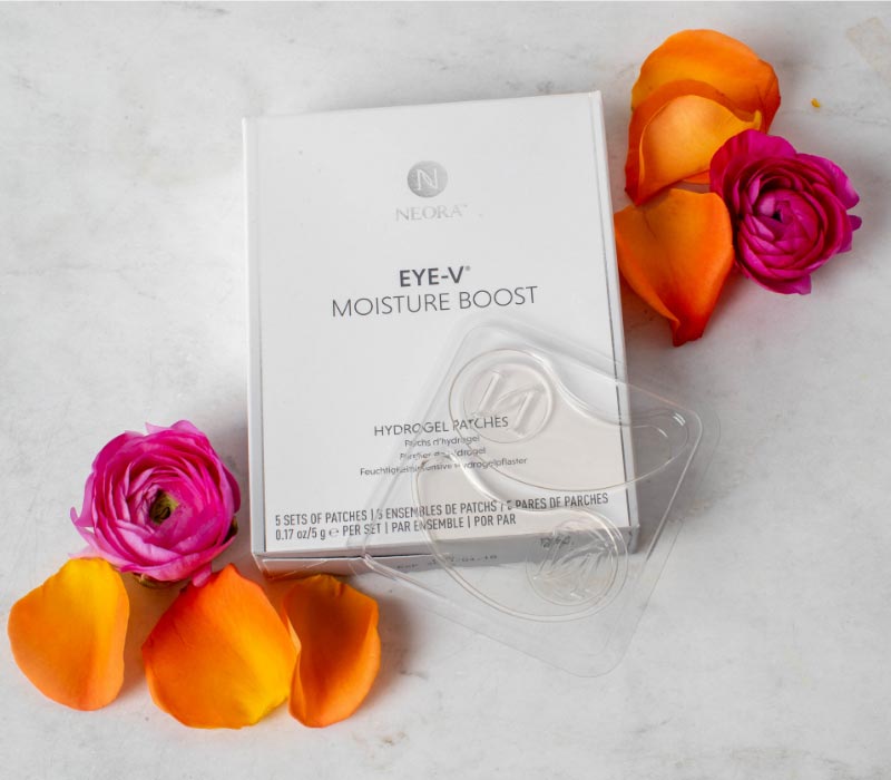 Neora’s Eye-V™ Moisture Boost Hydrogel Patches laying on a countertop next to rose petals